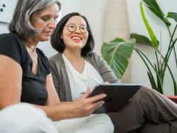 Zwei Mitarbeitende sitzen auf Sofa und besprechen Design auf Tablet